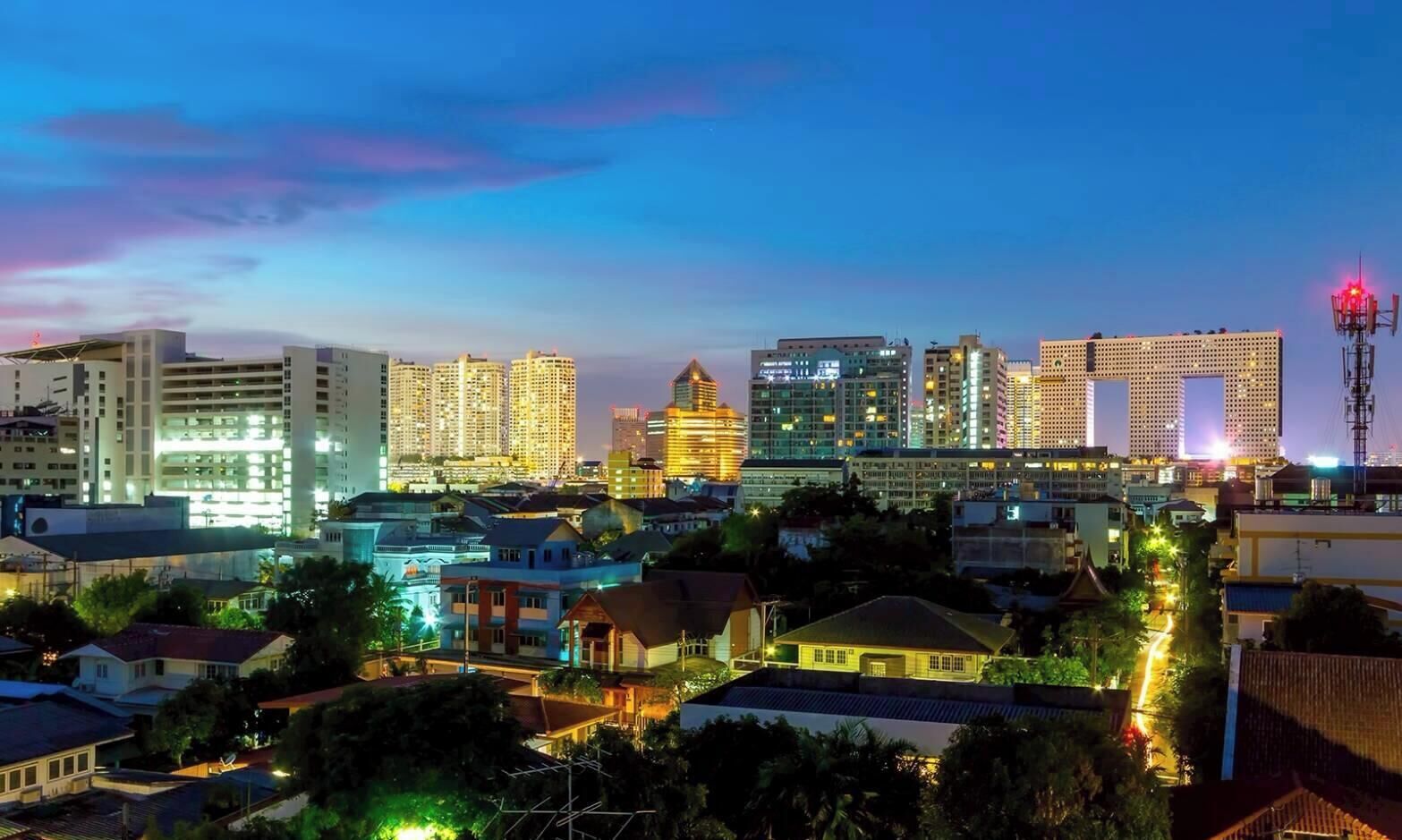 A cityscape at dusk with illuminated buildings and a clear sky.