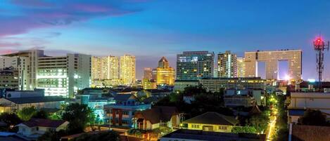 A cityscape at dusk with illuminated buildings and a clear sky.