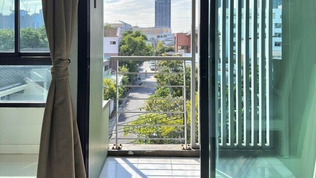 Una habitación moderna con un gran ventanal corredera que da a un balcón. El espacio tiene un diseño limpio y minimalista, con un amplio ventanal y una cortina.