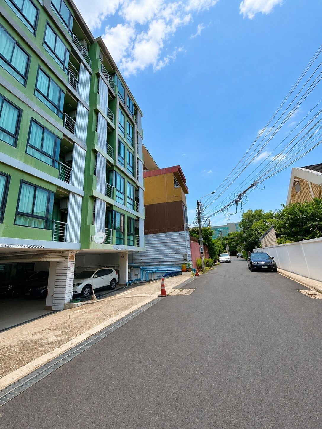 Un edificio de varios pisos con estacionamiento, cielo despejado y líneas eléctricas.