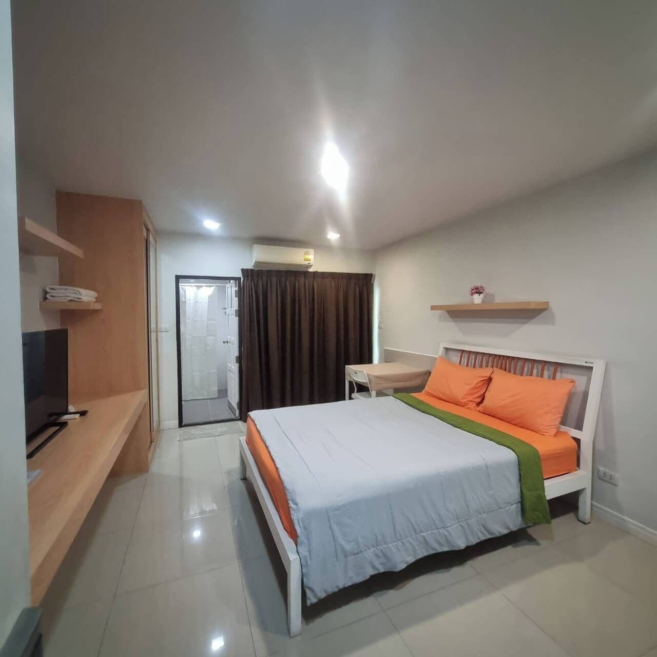 A hotel room with a bed, a TV, a desk, and a bathroom.