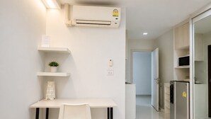 Una cocina moderna con encimera blanca, una silla blanca y un microondas integrado.