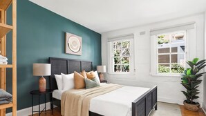A bedroom with a bed, bedside tables, a window, and a plant.