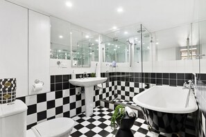 Features a bathtub, large mirror, and pedestal sink.