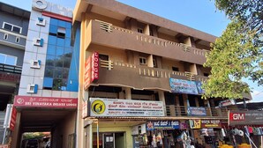 Um edifício de vários andares com espaços comerciais no andar térreo, incluindo uma loja de móveis e uma papelaria.