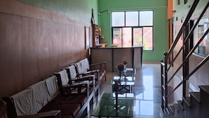 Uma sala de estar ampla com sofás, uma mesa de centro de vidro e uma escada que leva a um andar superior.
