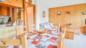 Una cocina acogedora con armarios de madera, una mesa de comedor con mantel acolchado y paneles de madera en la pared.