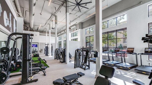 A spacious gym with various exercise equipment, large windows, and a high ceiling. - Charming 1-bedroom Haven I Frisco Dallas I Pool / Gym / Work Space (Frisco)