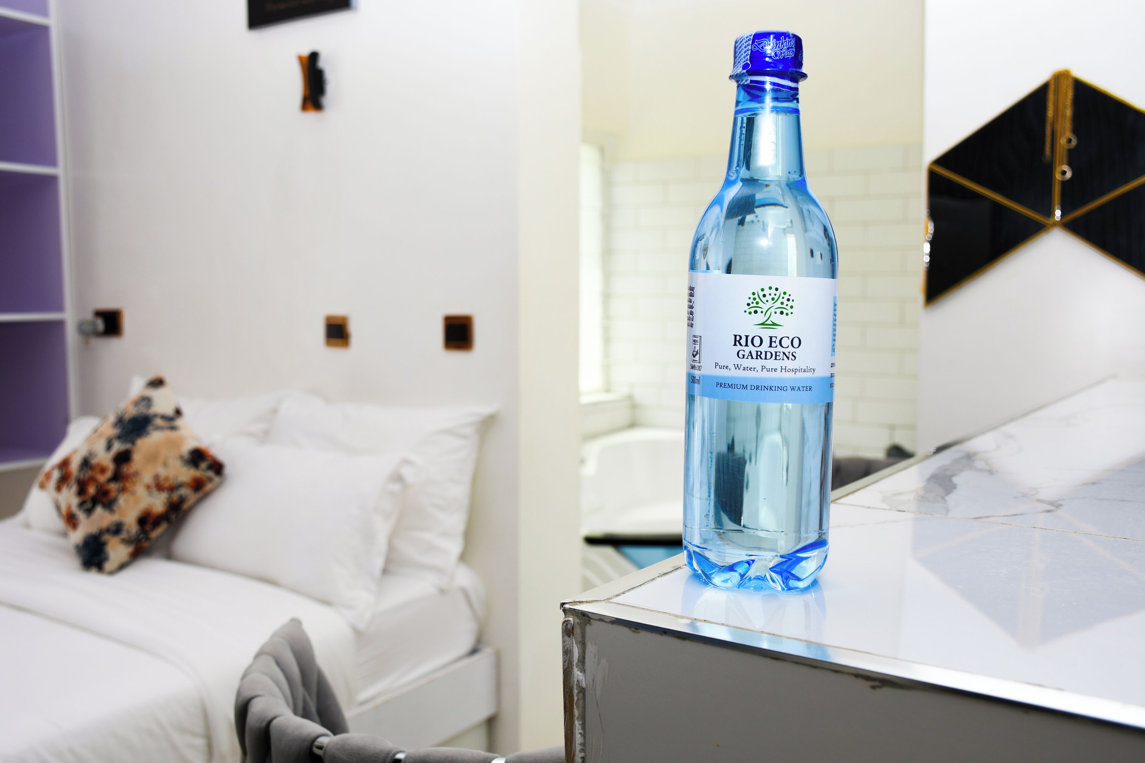 A bottle of Rio Eco Gardens premium drinking water on a table in a hotel room.