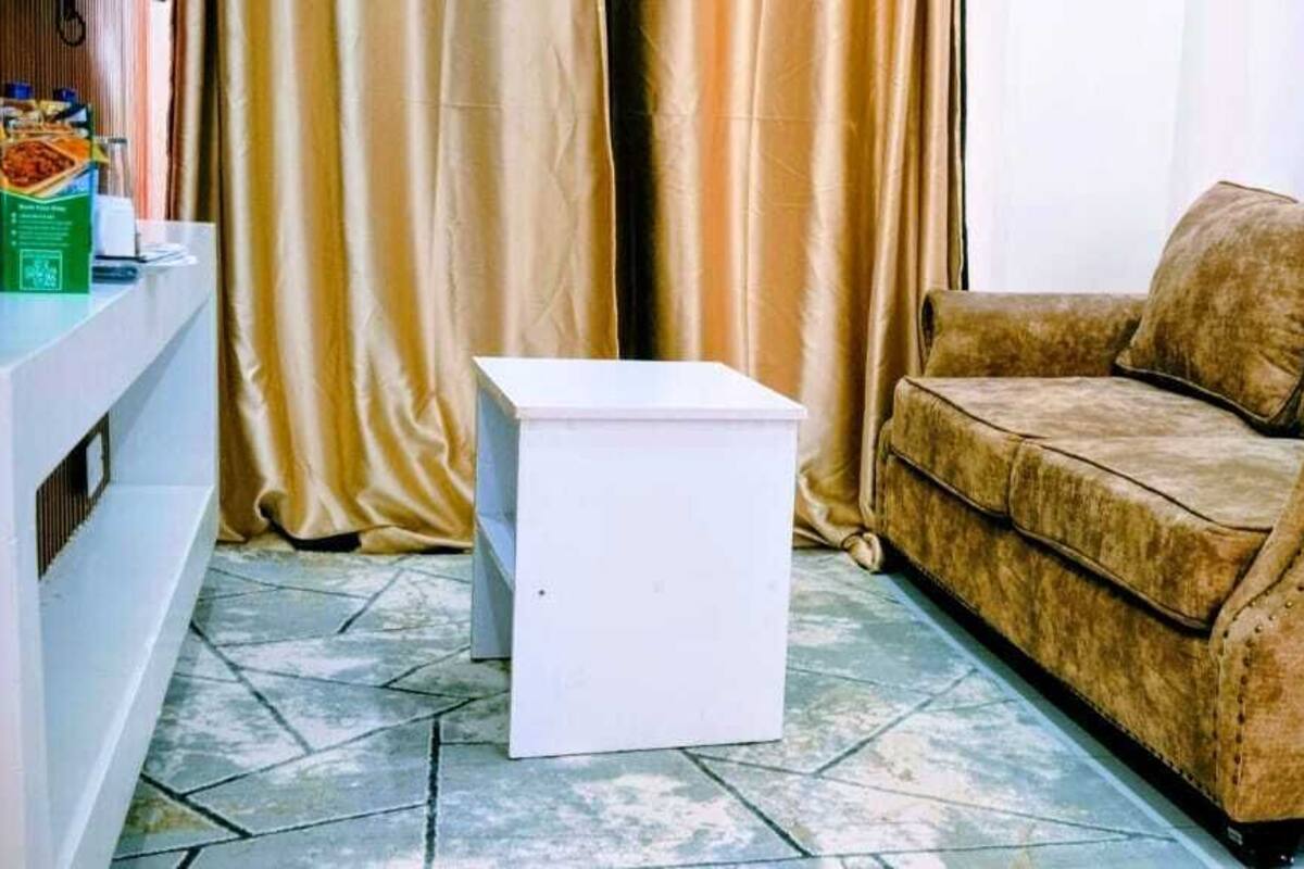 A living room with a brown sofa, a white cabinet, and a tiled floor.