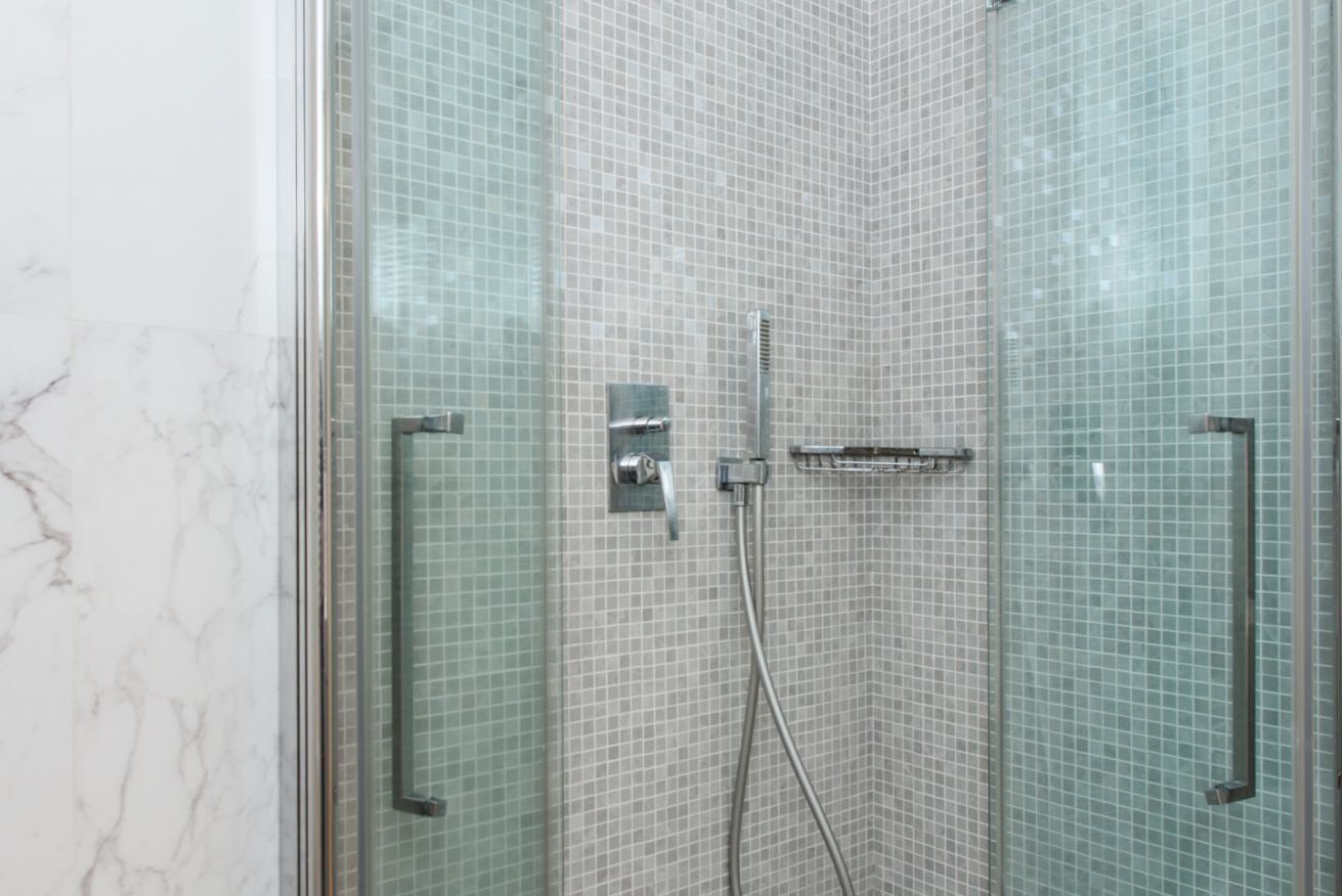 Une douche entièrementClose avec des parois en verre, un mur carrelé et un sol en marbre.