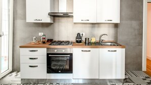 A modern kitchen with white cabinetry, a built-in oven, a gas stove, and a stainless steel sink.