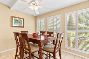 A dining area with a wooden table, chairs, and a ceiling fan.