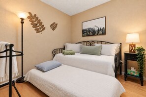 A hotel room with two beds, a bedside table with a lamp, a wall-mounted picture, and a towel rack. - Pine Ridge Retreat • Pool • Patio • Mountain Views (El Paso)