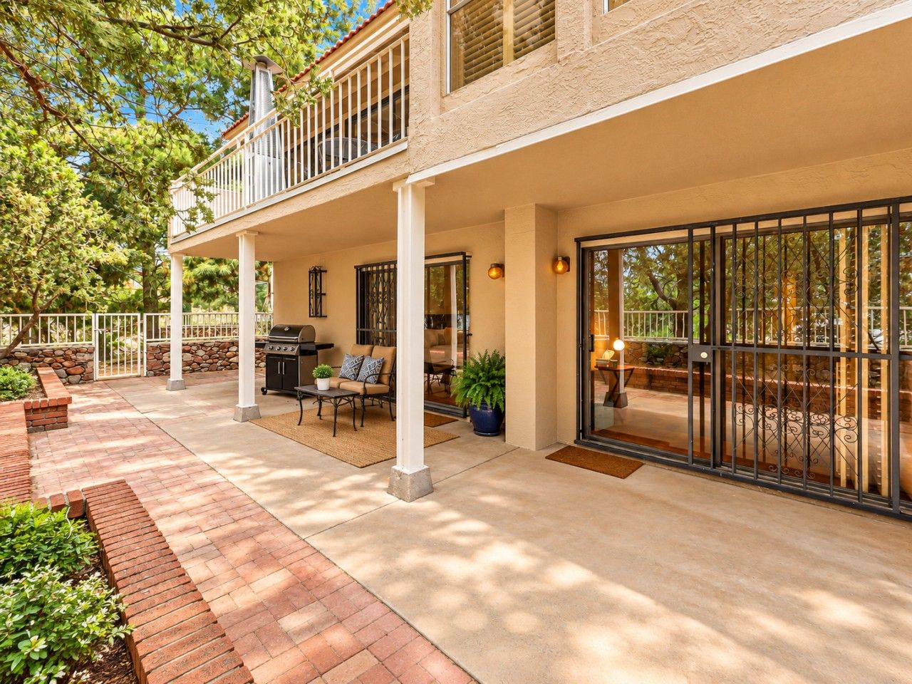 A covered patio area with outdoor furniture, a barbecue grill, and a view of the surrounding landscape.