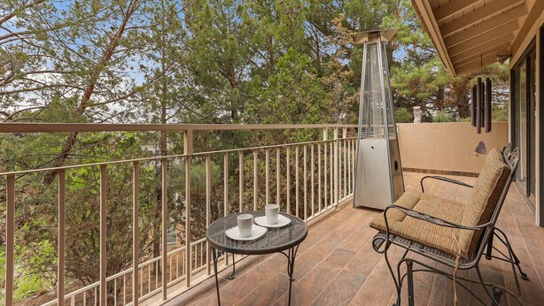 Ein Balkon mit Tisch, Stühlen, einem Grill und Blick auf Bäume.
