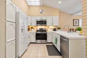 A modern kitchen with white cabinetry, stainless steel appliances, and a black herringbone-patterned floor mat. - Pine Ridge Retreat • Pool • Patio • Mountain Views (El Paso)