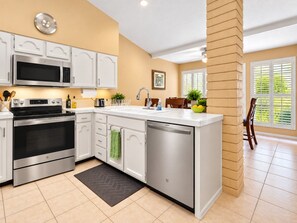 A modern kitchen with stainless steel appliances, white cabinetry, and a built-in dishwasher.