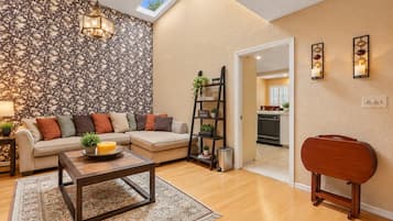 A living room with a sofa, coffee table, and a ladder shelf against a patterned wall.