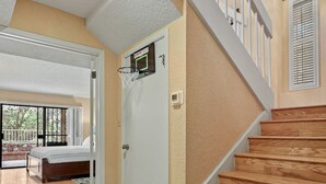 Eine Treppe mit Holzboden und weißen Geländern, die zu einem Raum mit einem Bett und einem Basketballkorb führt.