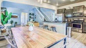 A modern kitchen with stainless steel appliances, a wooden dining table, and a staircase leading to another level.