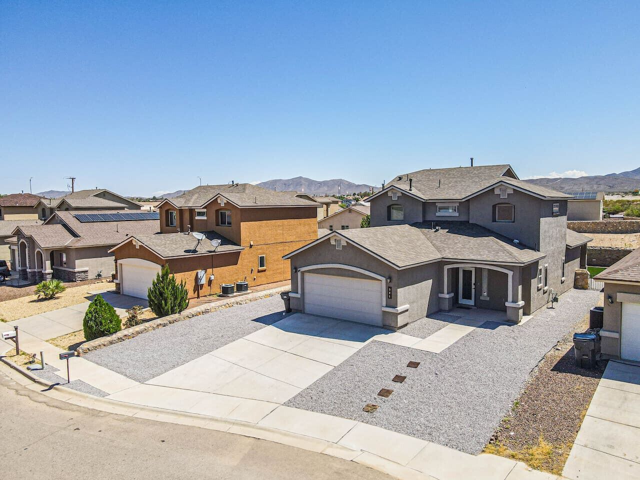 A residential area with houses featuring garage doors, driveways, and solar panels.
