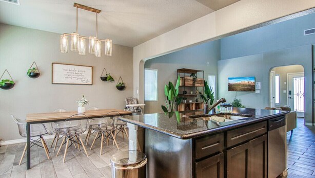 A modern kitchen with a central island, wooden dining table, and chairs.