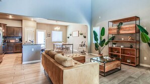 A spacious living area with a sofa, coffee table, and a wooden bookshelf.
