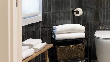 A bathroom with a wooden bench, a basket, and a toilet.