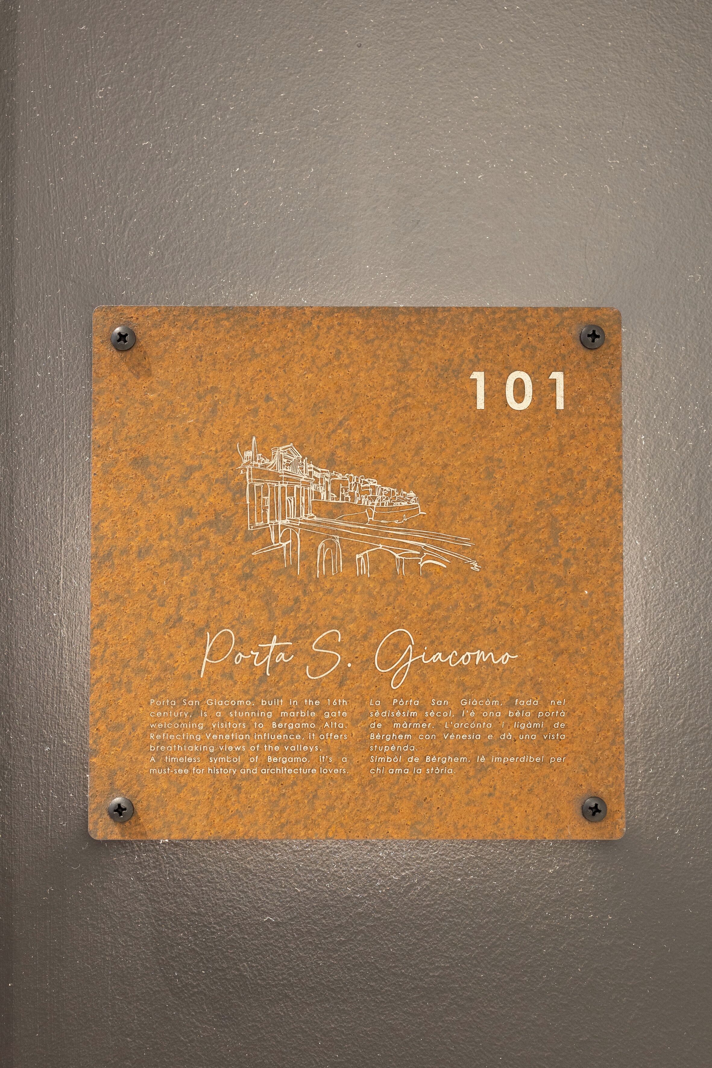 Eine Gedenktafel mit einer Illustration eines Marmortors und Text, der das Porta S. Giacomo, ein historisches Wahrzeichen in Bergamo, beschreibt.