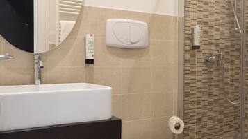 A bathroom with a sink, mirror, toilet, and shower.
