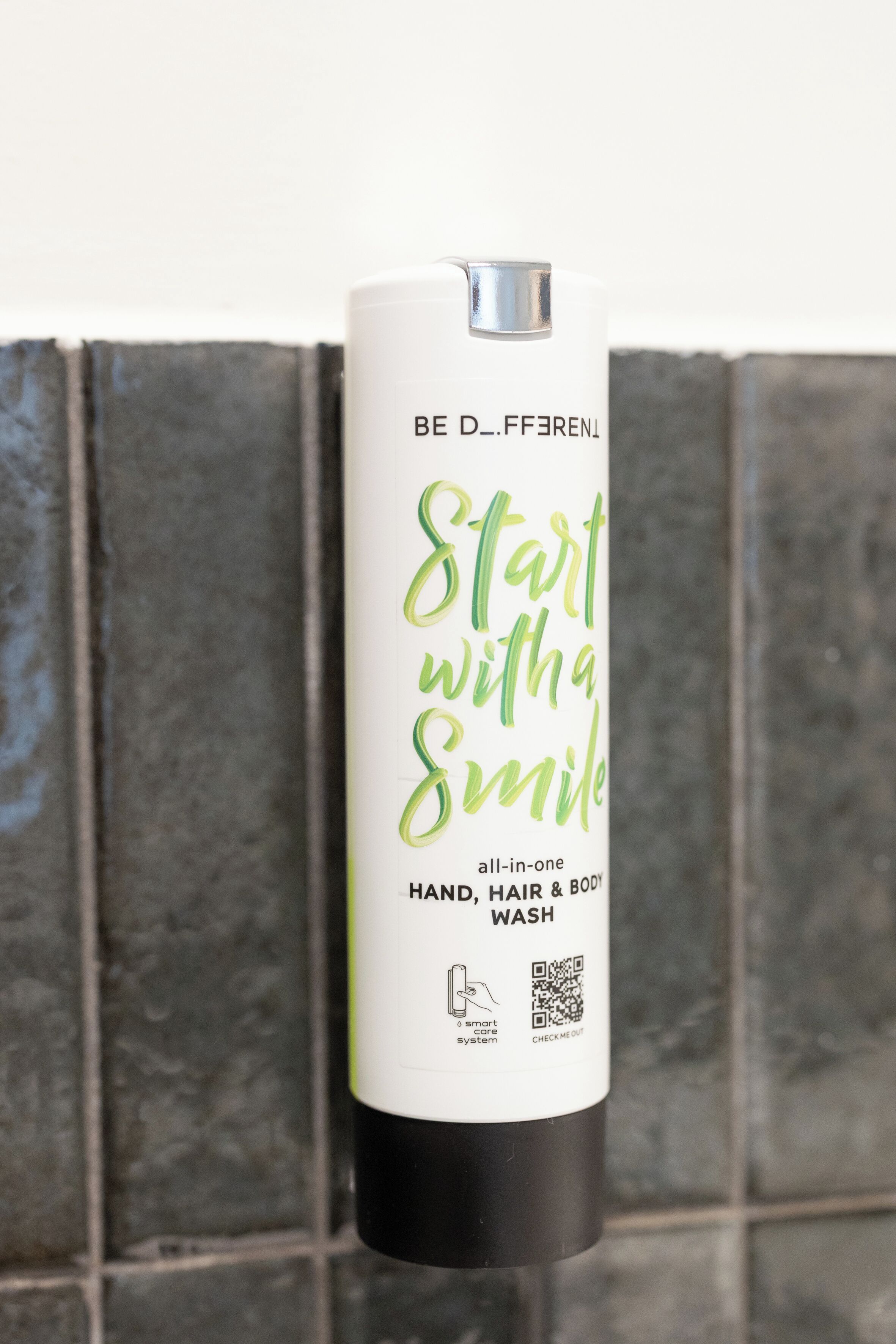A bottle of hand, hair, and body wash with a QR code and a smart care system icon.