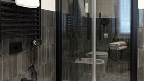 A modern bathroom with a glass-enclosed shower, a white sink, and a towel rack. - Porta Antica (Bergamo)