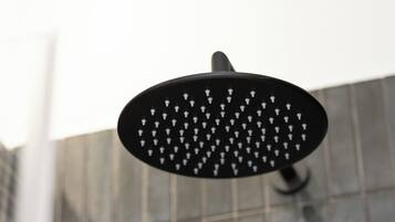 A showerhead with multiple nozzles against a tiled wall.