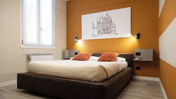 Une chambre à coucher comprenant un lit, deux tables de chevet fixées au mur, un radiateur et une grande fenêtre.