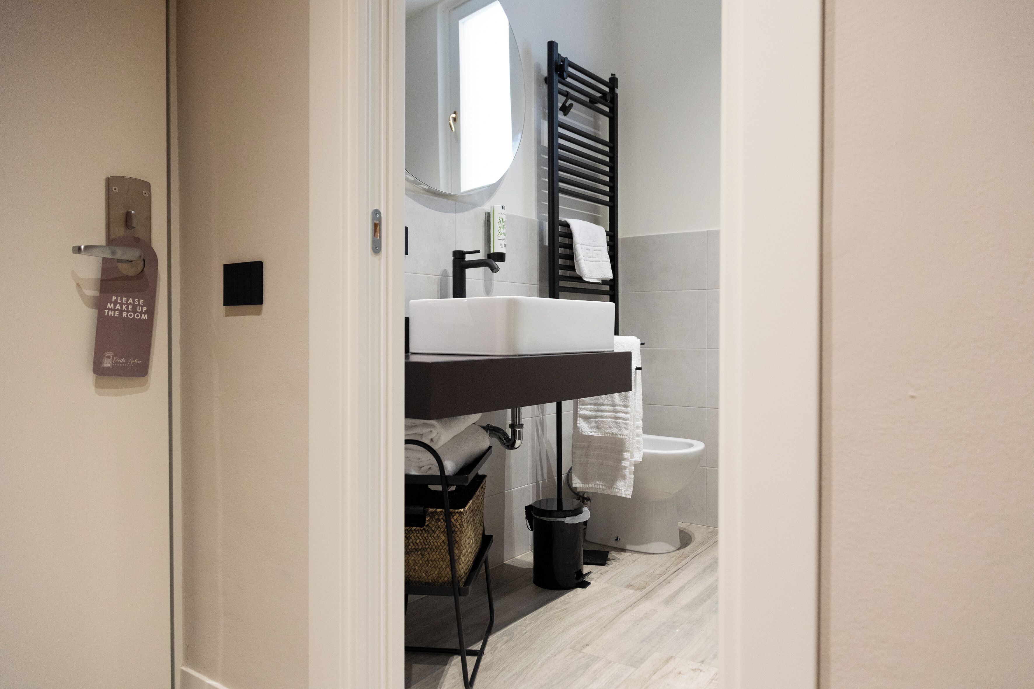A modern bathroom with a white sink, black towel rack, and a white toilet.
