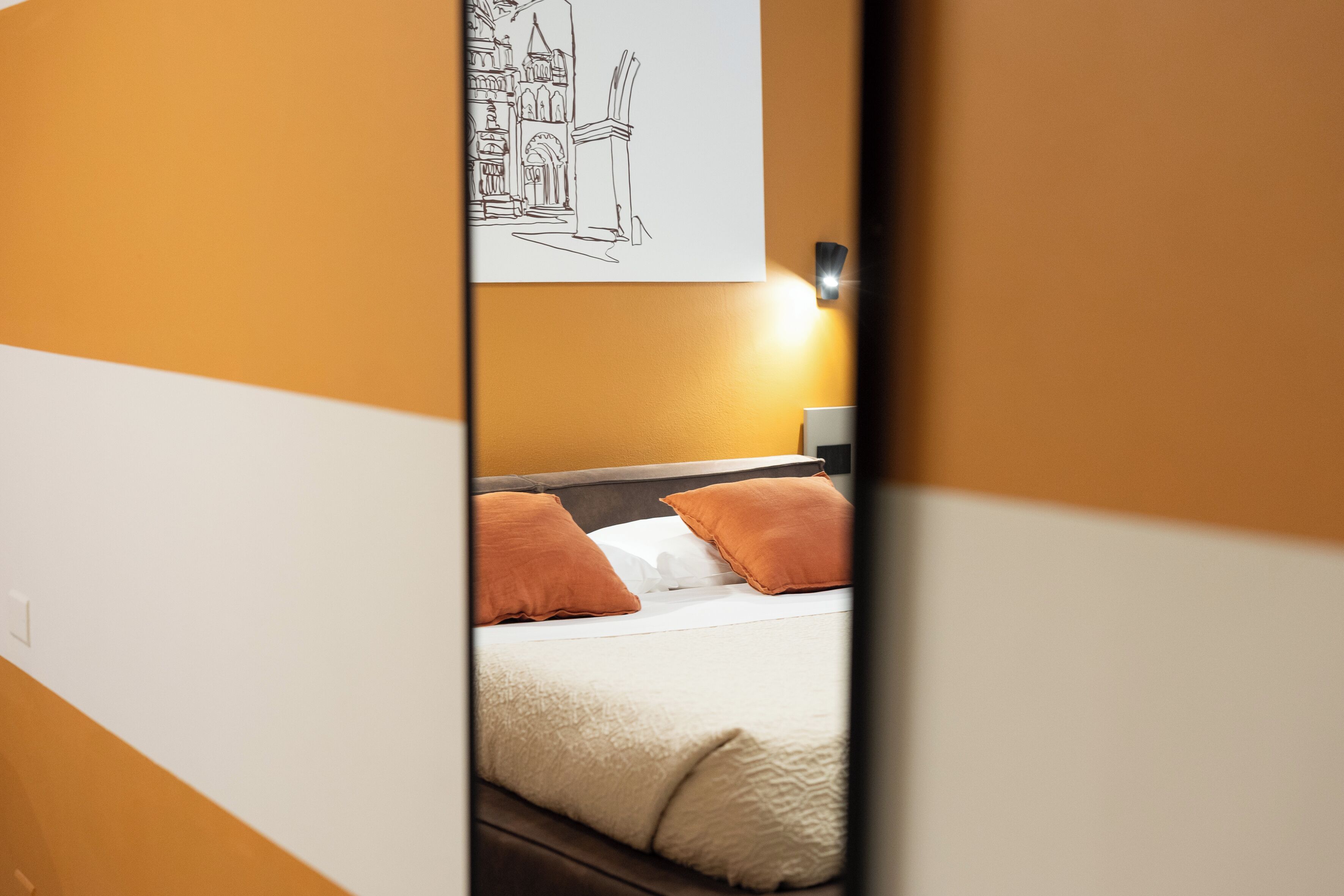 Ein Hotelzimmer mit einem Bett, zwei Kissen, einem Nachttisch und einem an der Wand hängenden Kunstwerk.