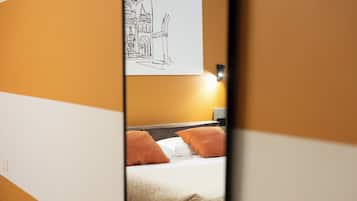 Ein Hotelzimmer mit einem Bett, zwei Kissen, einem Nachttisch und einem an der Wand hängenden Kunstwerk.