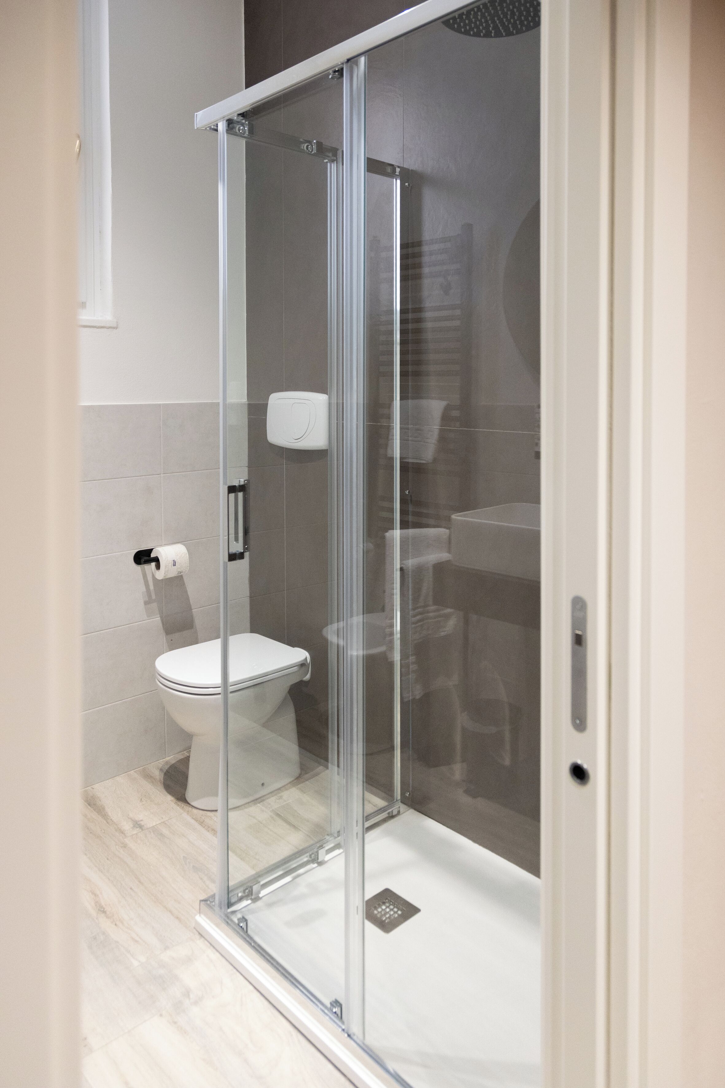 A modern bathroom with a glass shower enclosure, a toilet, and a sink.