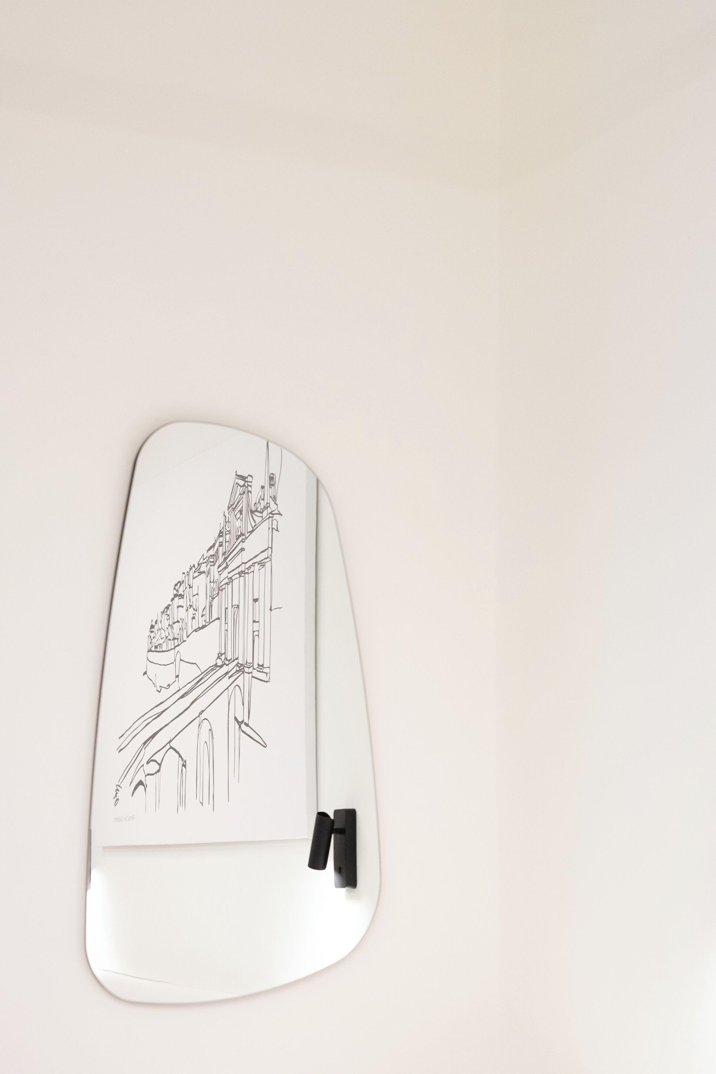 A white, curved object with a line drawing of a building and a bridge.