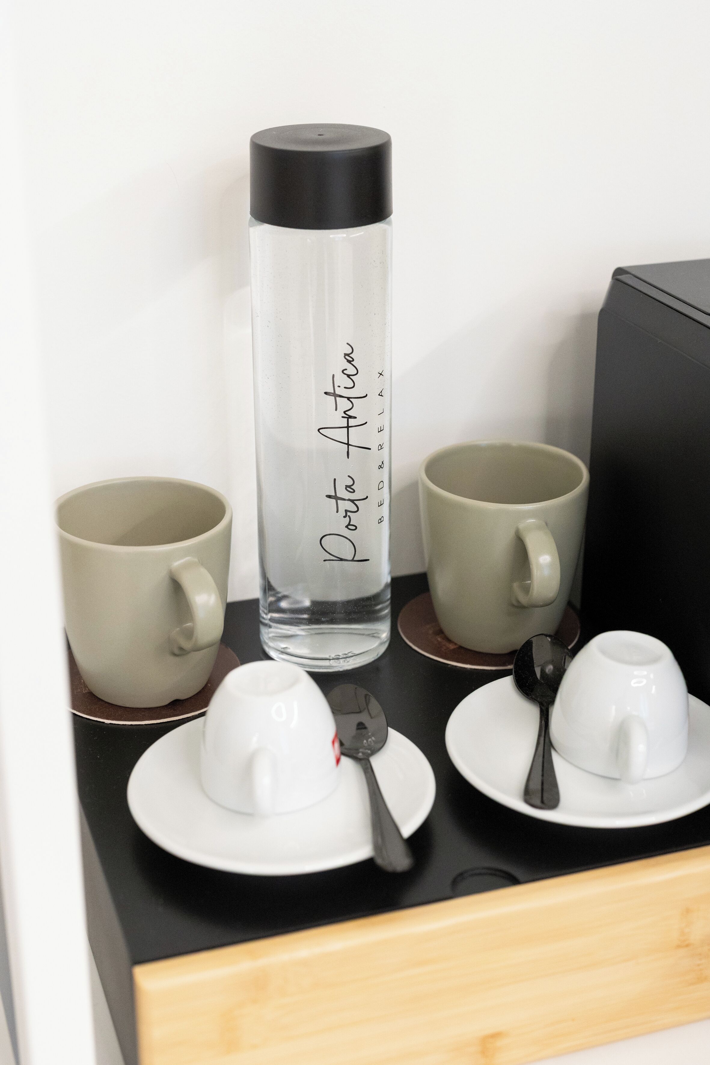 A table with a water bottle, two mugs, and a teapot with a spoon.