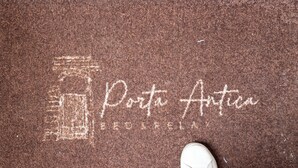 A brown textured floor with a chalk drawing of a building and the words "Porta Antica" and "GEOSFERA" visible. - Porta Antica (Bergamo)