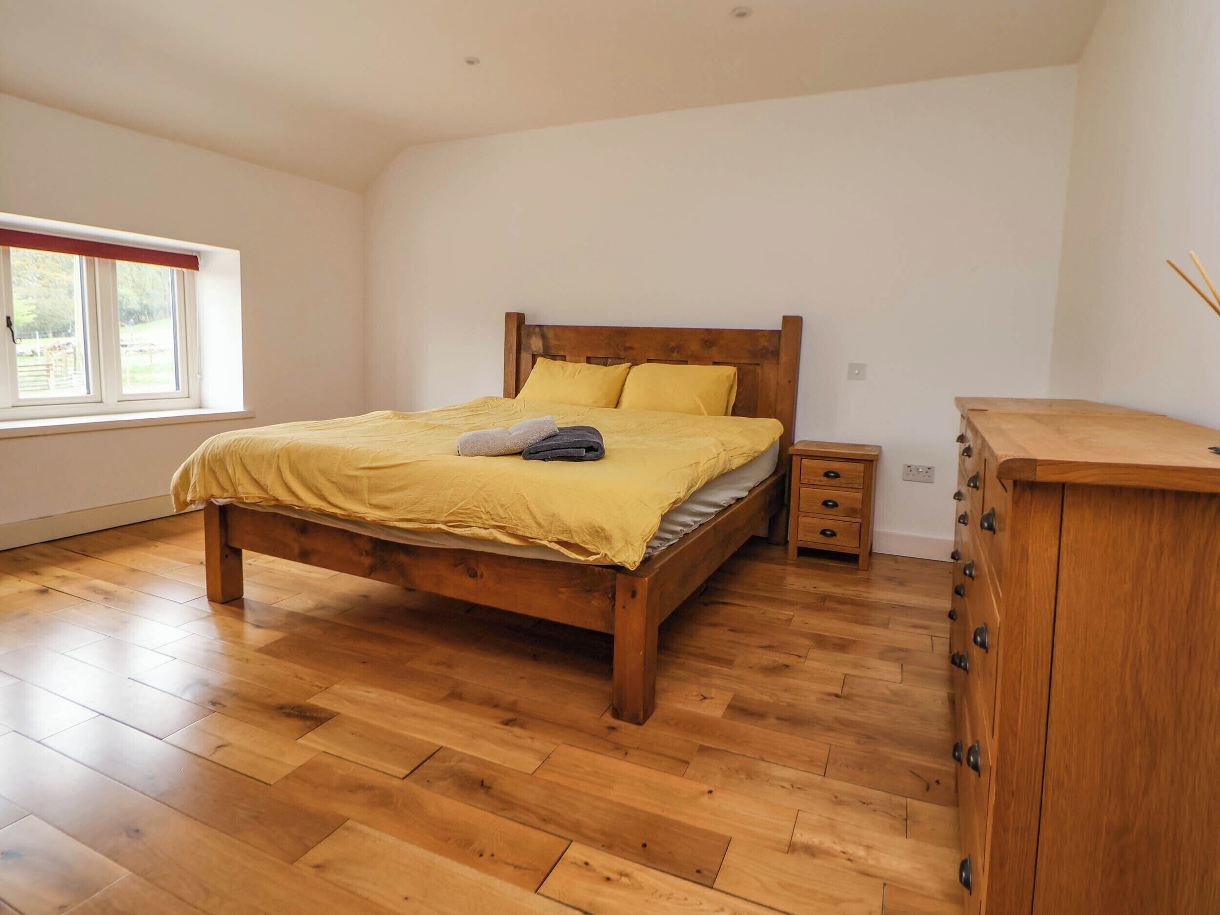 A bedroom with a wooden bed, a nightstand, and a wooden dresser.