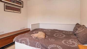 A bedroom with a bed, a bench, and two framed pictures on the wall.
