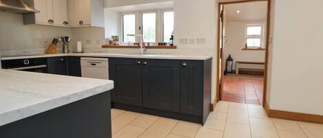 A modern kitchen with dark cabinets, a marble countertop, and a window above the sink.