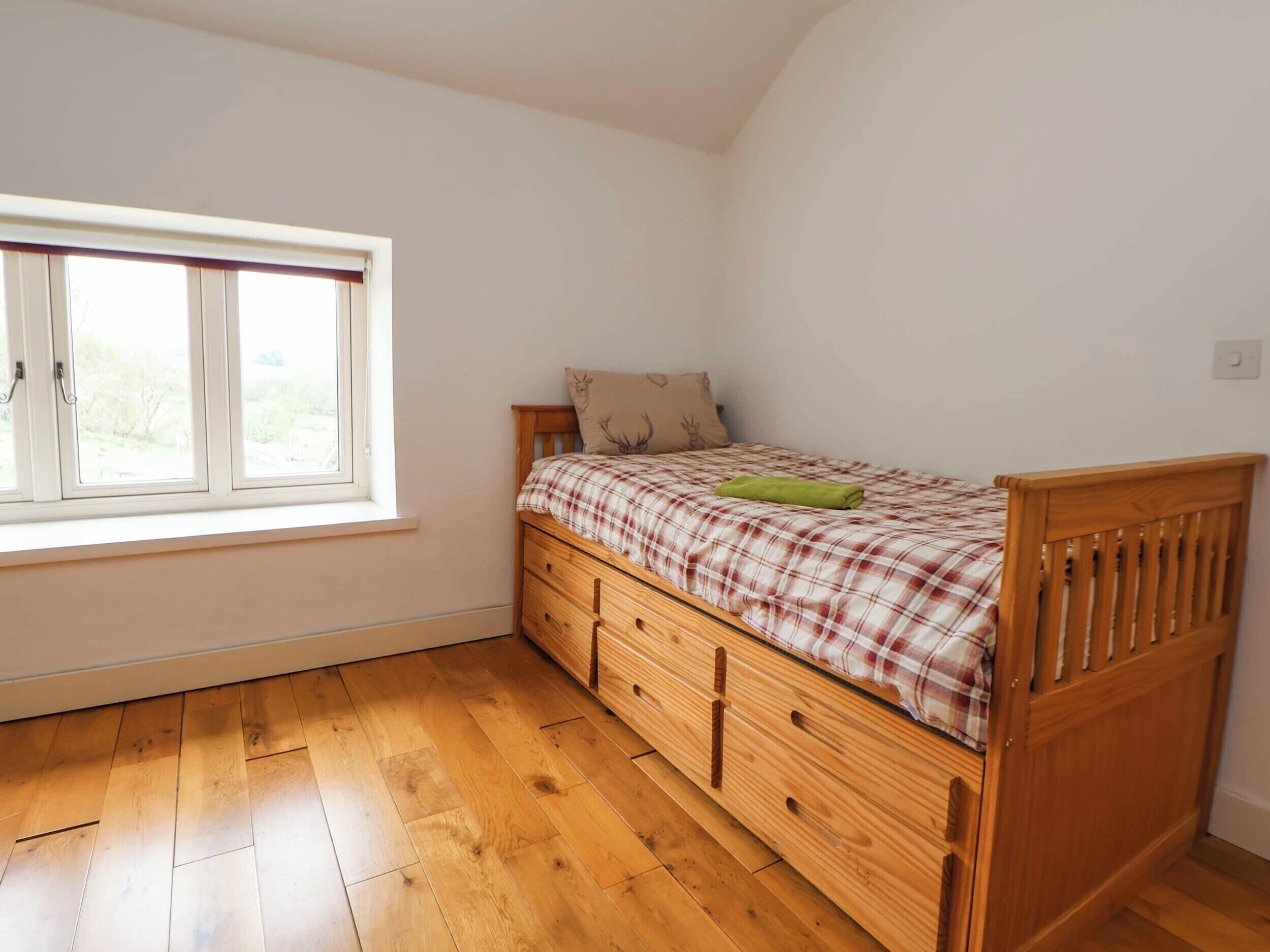 A bedroom with a wooden bed, a window, and a wooden floor.