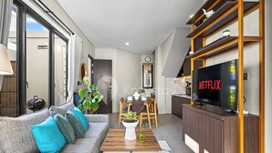Un salon moderne comprenant un canapé, une table basse, un téléviseur et un coin repas avec des chaises et une table.