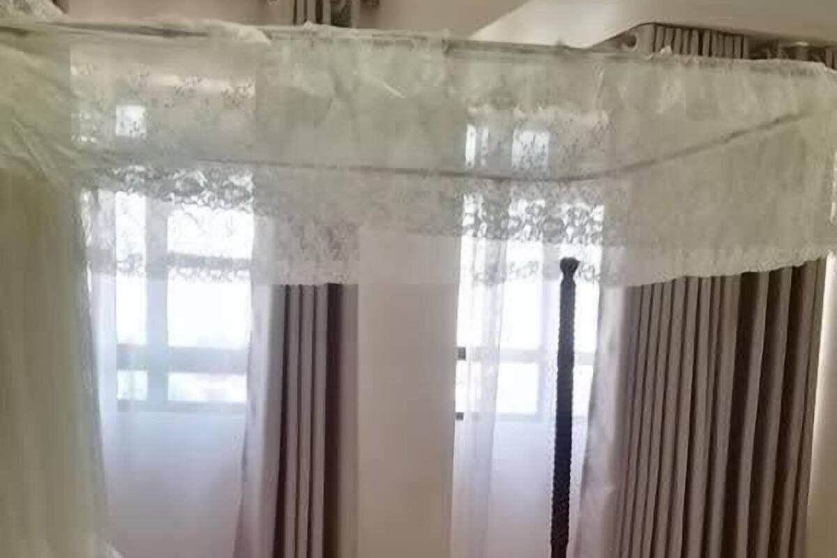 Ein Hotelzimmer mit Bett, Nachttisch, gemustertem Teppich und einem Fenster mit Vorhängen.