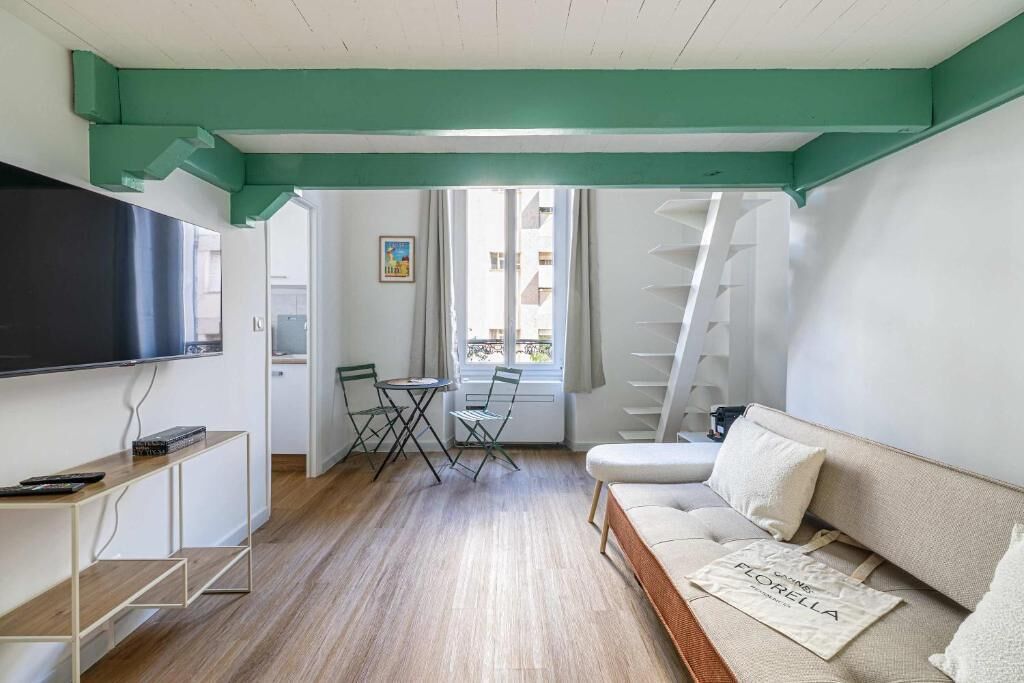 Un soggiorno moderno con un divano, una TV, un tavolino e una finestra vista edifici.