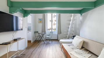 Un soggiorno moderno con un divano, una TV, un tavolino e una finestra vista edifici.